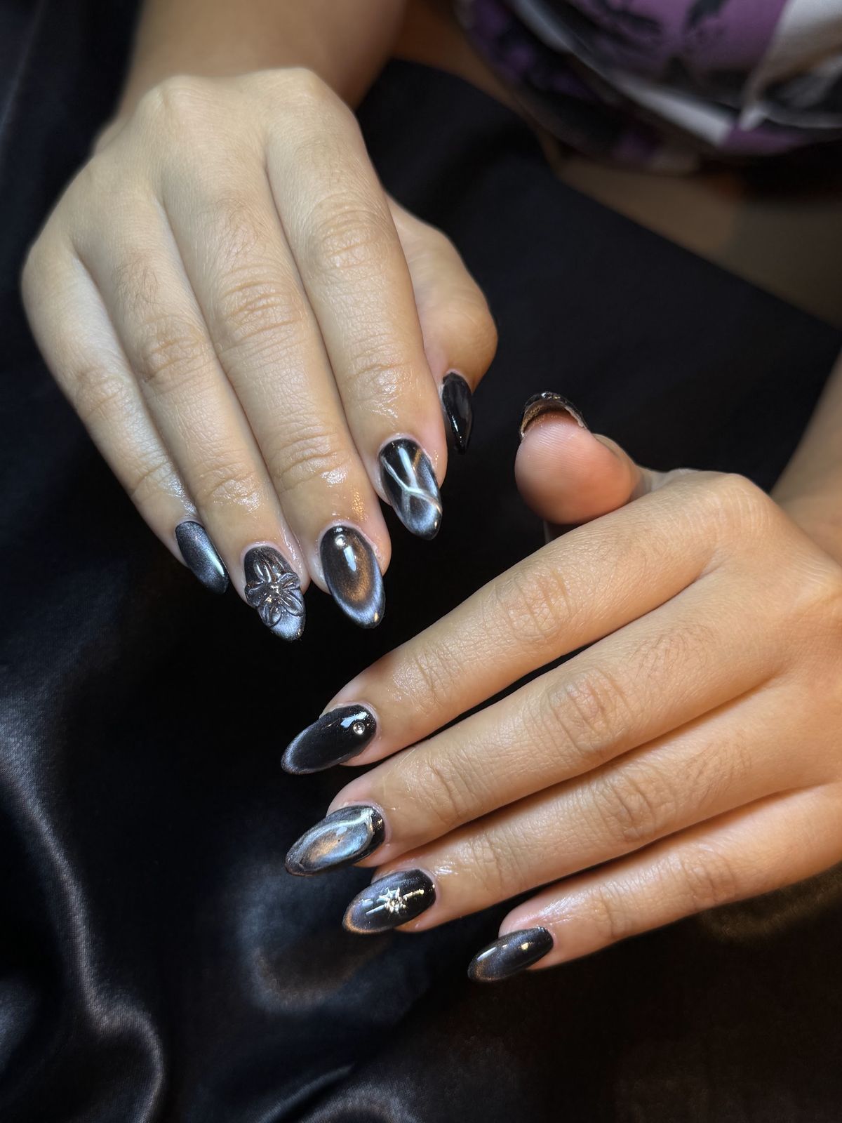 Zwarte chrome en cat eye op lange amandelnagels, op zwart satijn