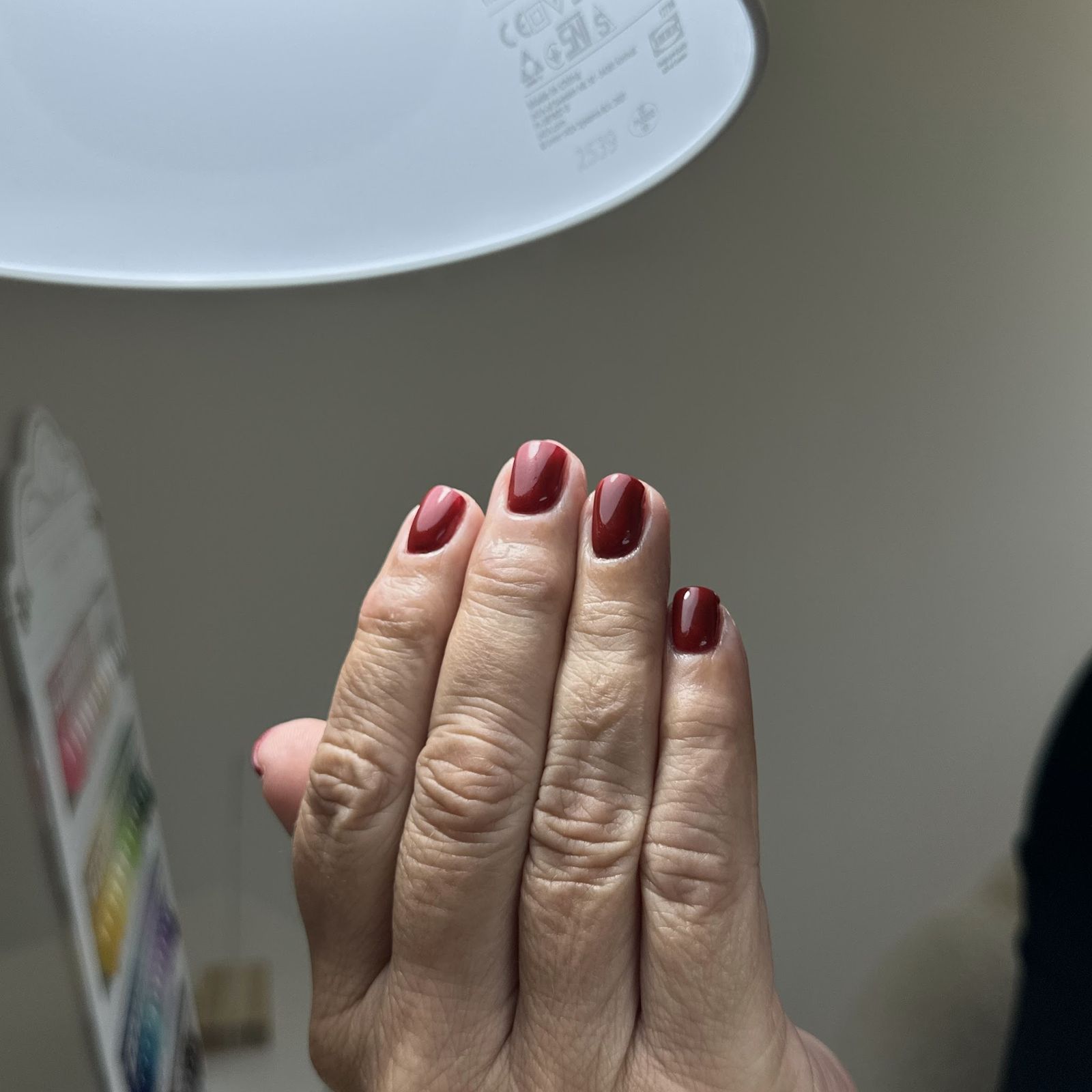 Dieprode korte nagels onder de werklamp