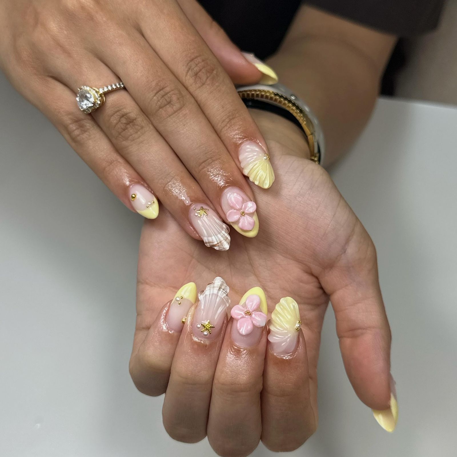 Gele schelptips met een roze 3D-bloem en een gouden zeester