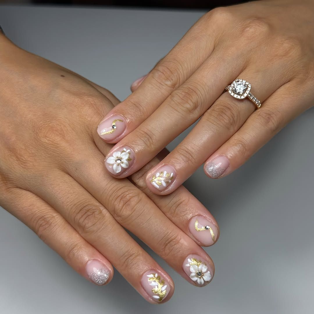 Korte nude nagels met witte bloemen en bladgoud